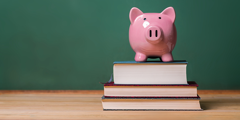 pink piggy bank on top of books with chalkboard in the background