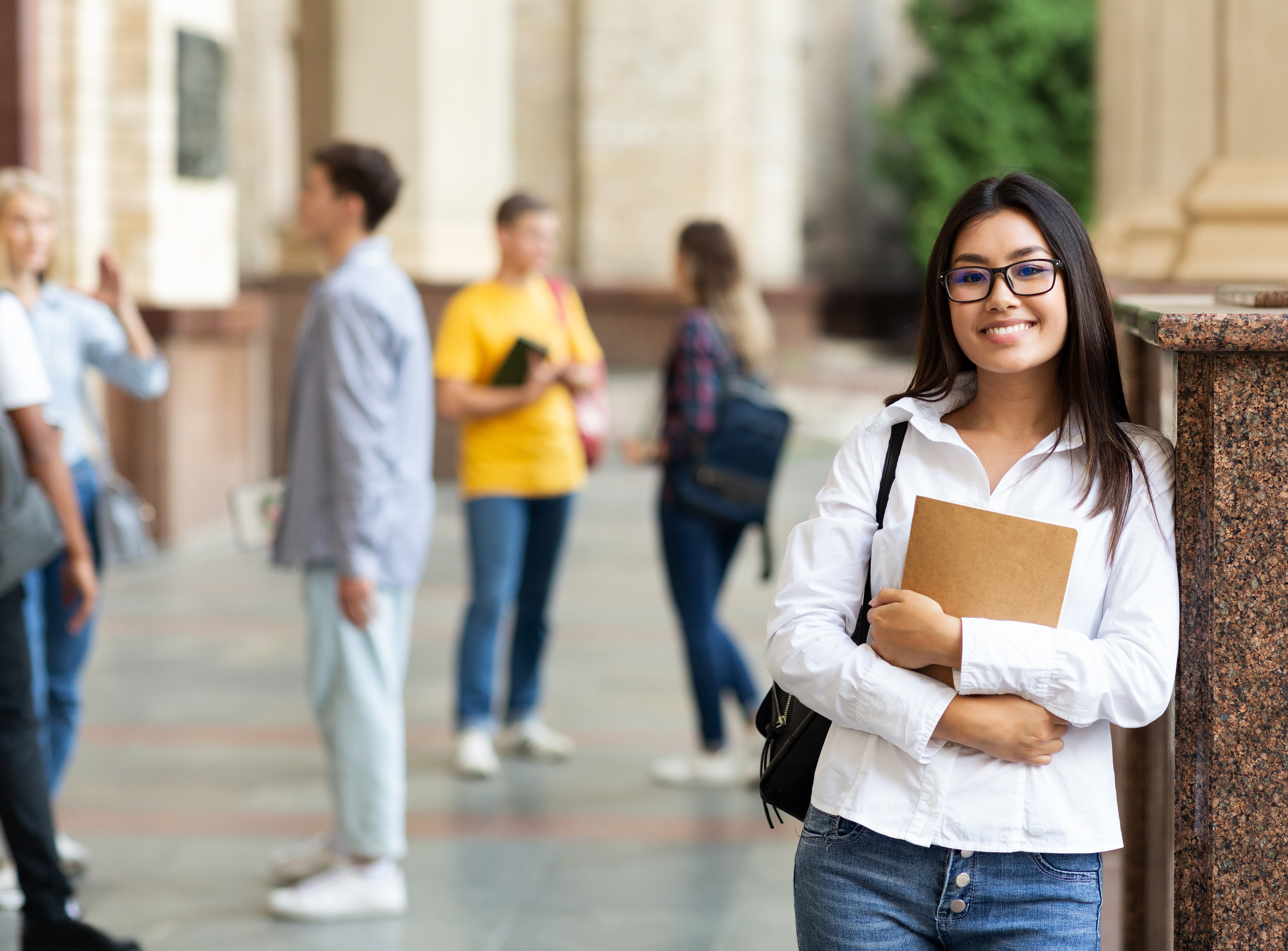 University life. Asian woman holding books and smiling.