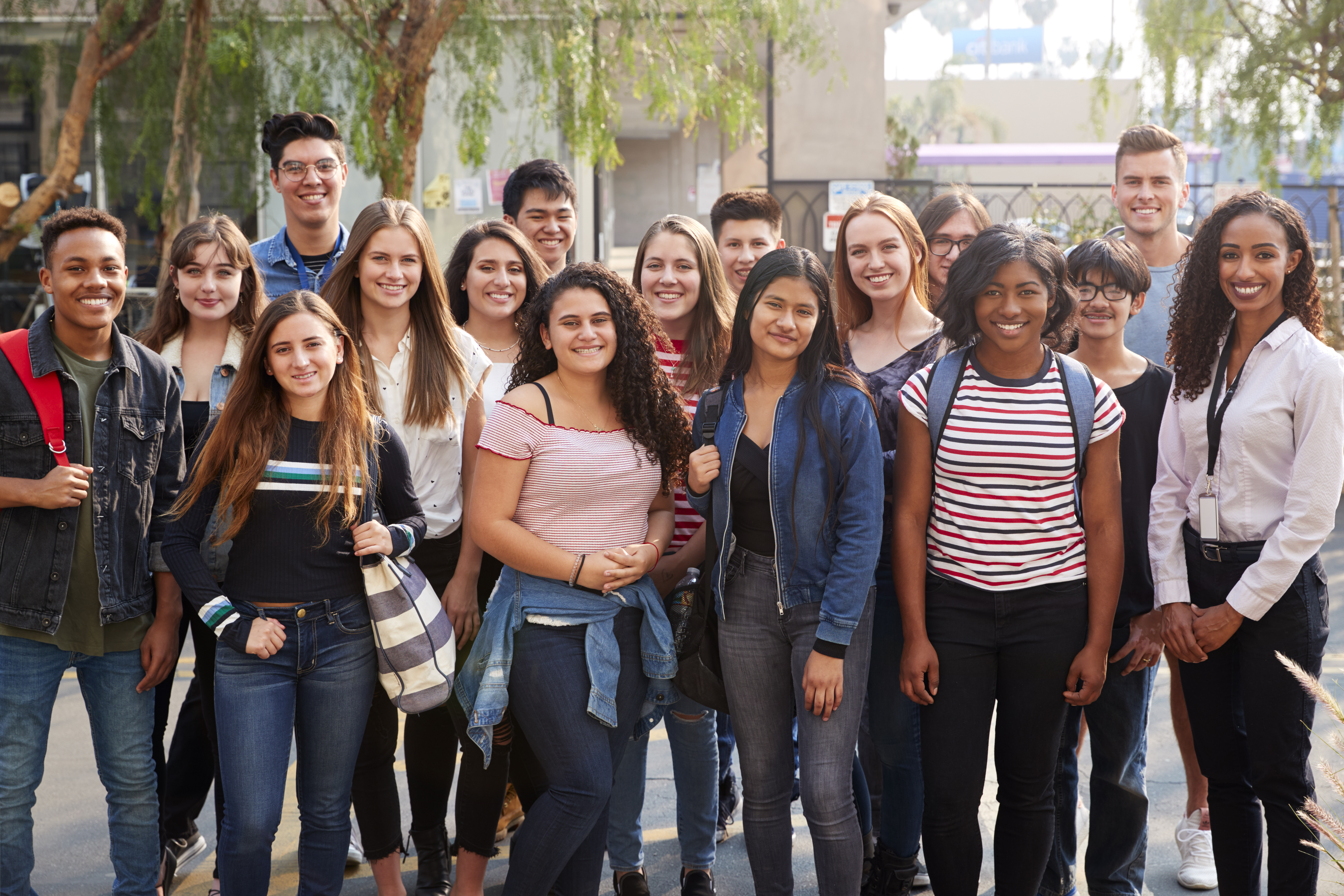 Portrait Of Smiling Male And Female College Students With Teachers Outside School Building