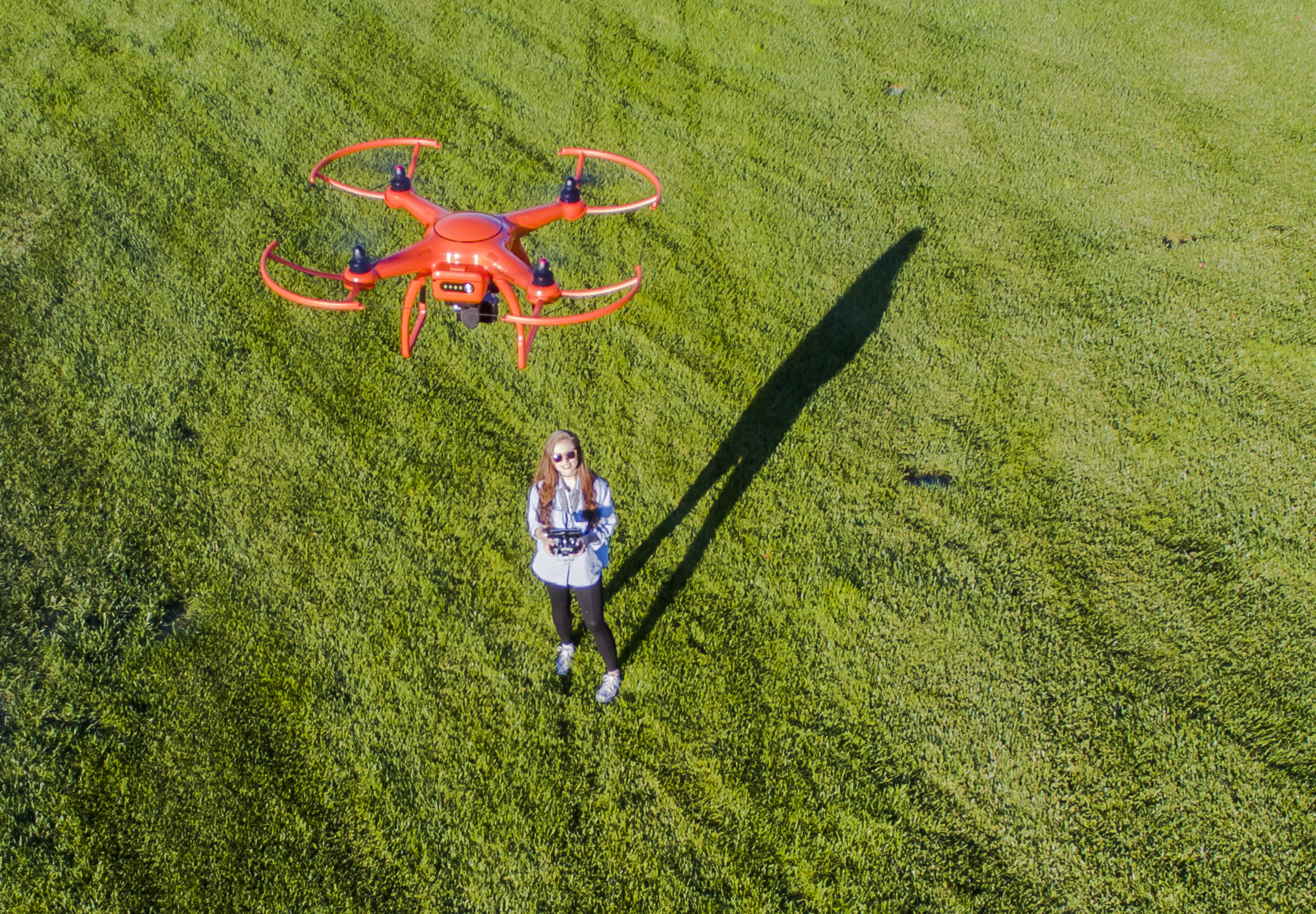 A brunette coed flying a drone in the outdoors