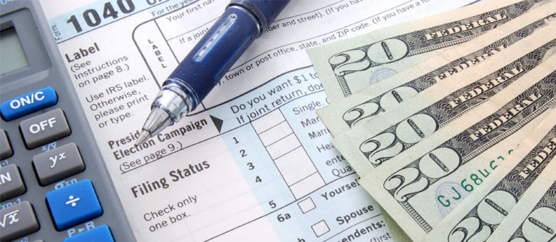 Tax form, calculator, pen and five $20 bills