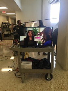 Ezra and her scene partner are seen on a TV monitor, a preview of what they look like on camera.   